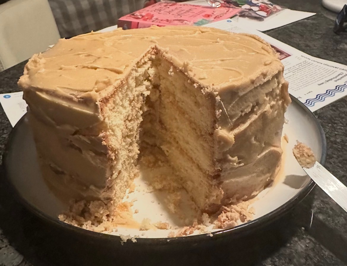 Tall homemade frosted layer cake with slice removed